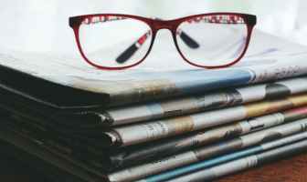 red framed eyeglasses on newspapers